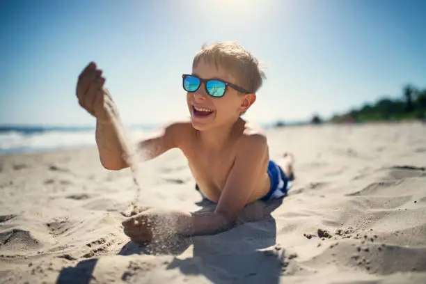 Photo of Little boy playing with sand on the beach
