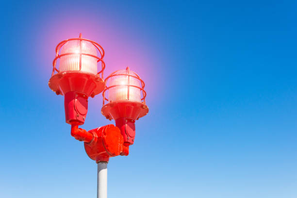 Red warning warning light with the light on, against the blue sky. Close up aircraft warning light on top of a highrise of building in evening time. for safety concept