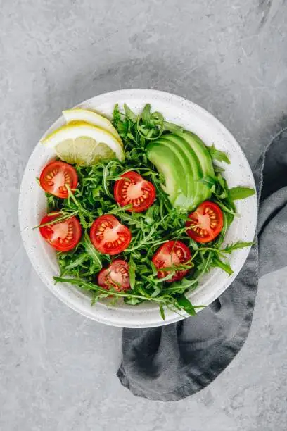 Green salad with leaves of arugula, tomatoes and avocado. Healthy summer lunch
