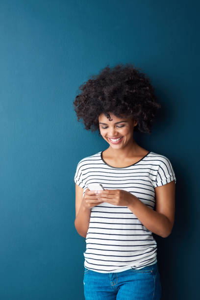 She never gets left out of the conversation Studio shot of an attractive young woman using a cellphone against a blue background never stock pictures, royalty-free photos & images