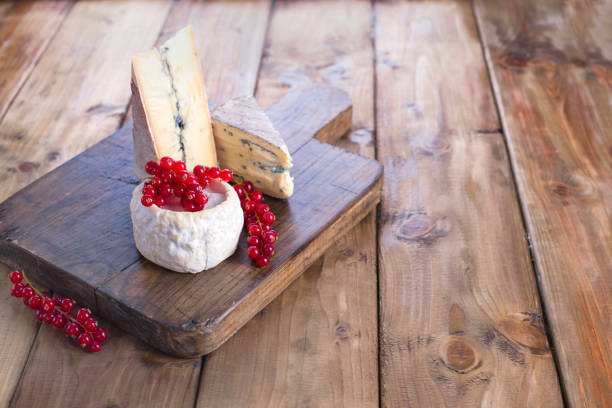 istock Different cheese with white and blue mold. A fresh red currant berries. White flowers. Wooden background and free space for text or advertising. copy space 970074062