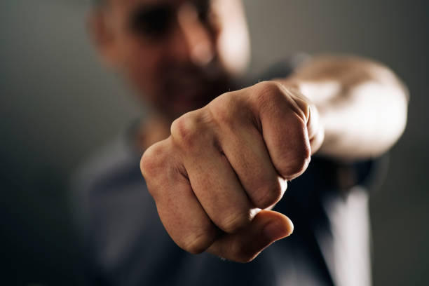 young man throwing a punch closeup of a young caucasian man throwing a punch to the observer, with a dramatic effect aggression photos stock pictures, royalty-free photos & images