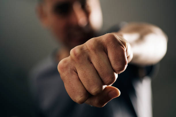 young man throwing a punch closeup of a young caucasian man throwing a punch to the observer, with a dramatic effect violence boxing fighting combative sport stock pictures, royalty-free photos & images