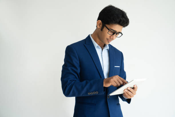 sérieux homme beau concentré avec tablette - indian culture manager men asian ethnicity photos et images de collection