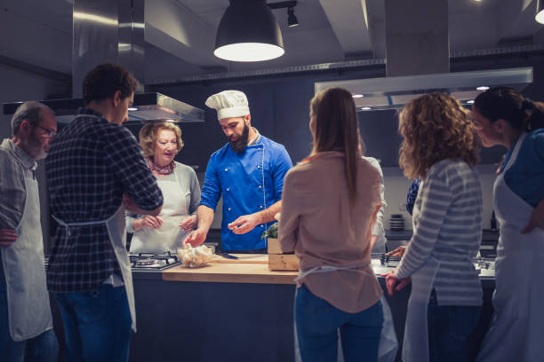 Chef assisting cooking class Chef is talking to attendees of cooking class, demontrating, answering questions. cooking show stock pictures, royalty-free photos & images