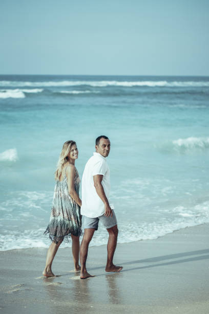 istock Smiling Couple Holding Hands and Strolling on Beach 970096764