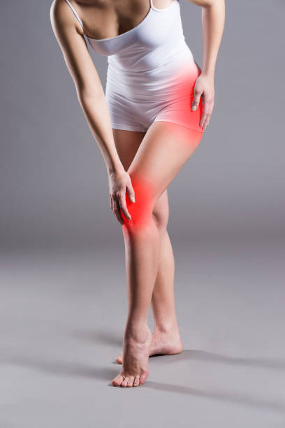 Pain in knee, joint inflammation, on gray background Woman with pain in thigh and knee on gray background, studio shot hamstring injury stock pictures, royalty-free photos & images
