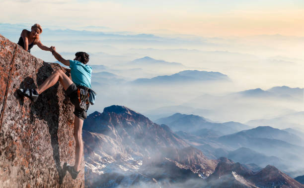 pareja de trabajo en equipo ayudando a mano confiar en inspiradoras montañas - aspirations mountain hiking climbing fotografías e imágenes de stock