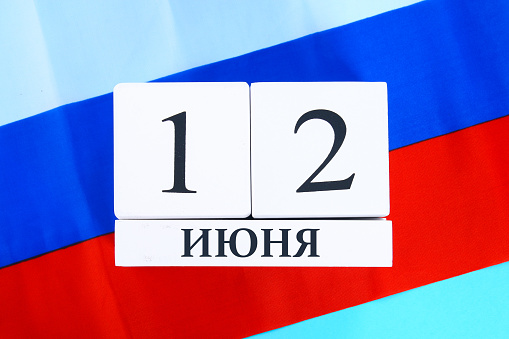 The inscription is June 12, the Day of Russia. Wooden white calendar on the background of the flag of Russia