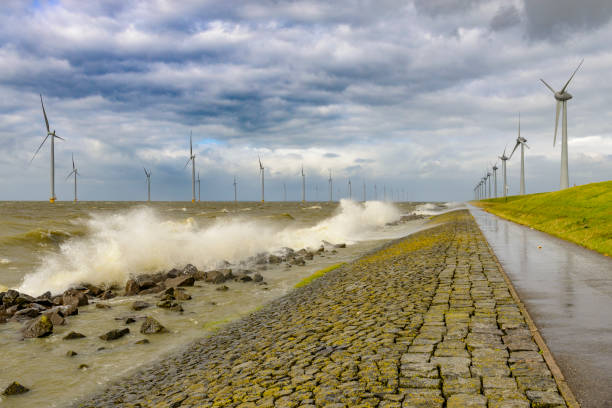 Wind farm with rows of wind turbines both on land and offshore during a winter storm at the shore of the IJsselmeer in the Noordoostpolder, Flevoland, The Netherlands.