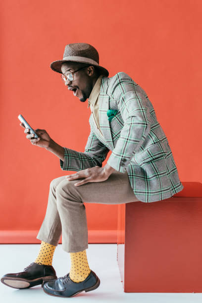 istock handsome excited african american man using smartphone, on red 970109392