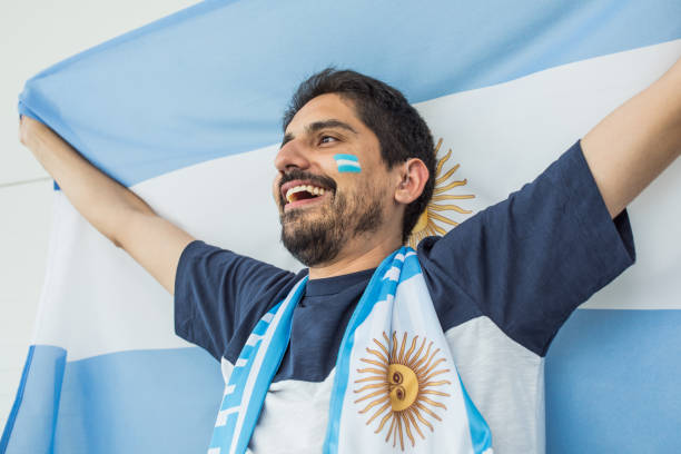 Soccer fan cheering at the game. Holding national team flag, with color paint on face. Studio shot