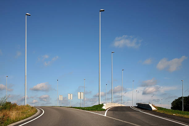 Split road with streetlights against a blue sky stock photo