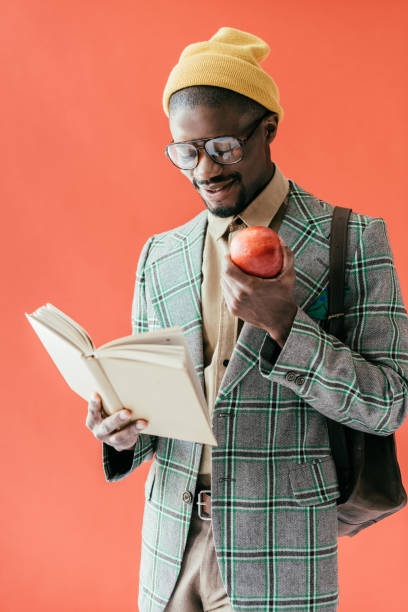 istock african american man with apple reading book, isolated on red 970112994