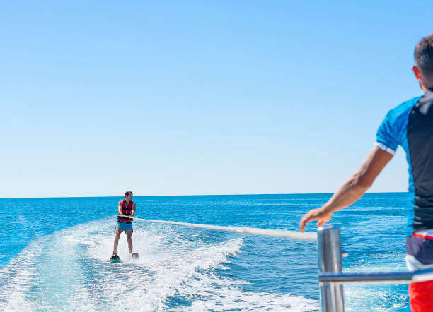 jeune homme glisse ski nautique sur les vagues sur la mer, l’océan. mode de vie sain. émotions humaines positives, joie. famille à océan tropical pendant le jour. vacances de printemps et d’été. - ski boat photos et images de collection