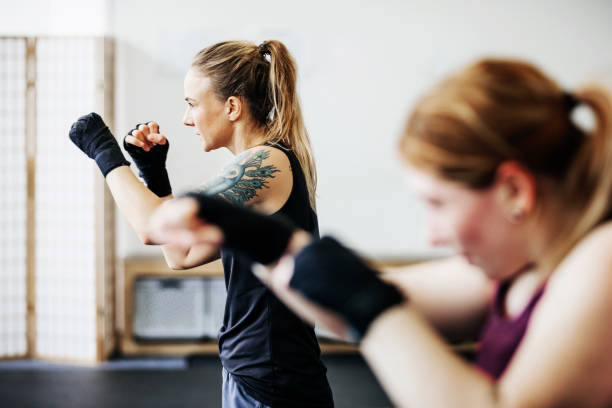 Amateur Kickboxers Shadow Boxing Together A group of amateur kickboxers practicing drills together and shadow boxing at their local gym. women boxing sport exercising stock pictures, royalty-free photos & images