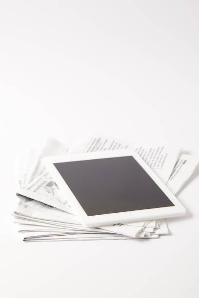 istock digital tablet with blank screen on pile of newspapers, on white 970139058