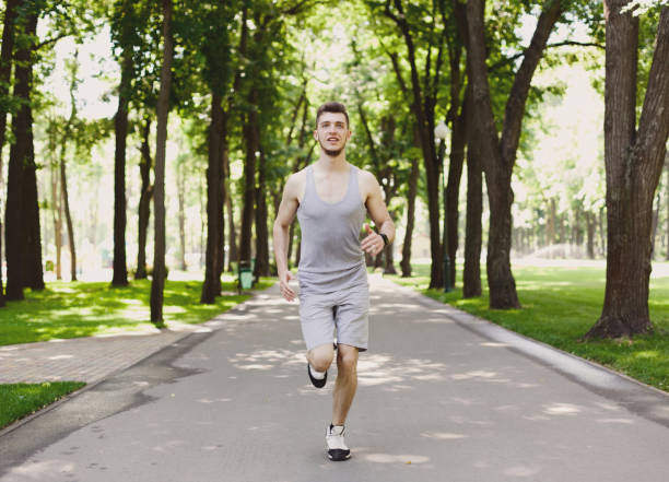 istock Young man running in green park, copy space 970160462
