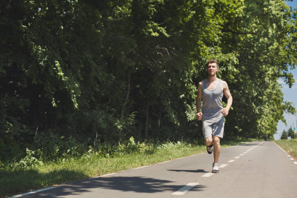 istock Young man jogging on treadmill in park, copy space 970161022
