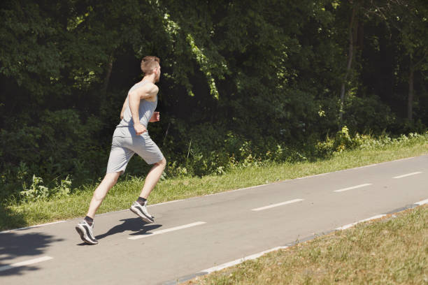 istock Young man jogging on treadmill in park, copy space 970161146