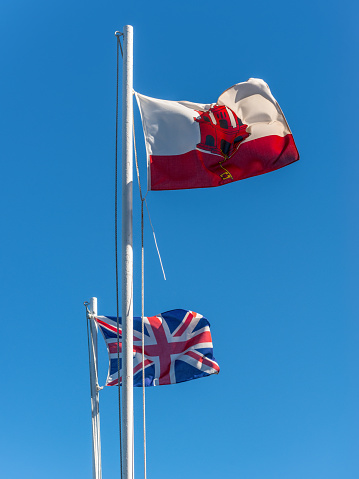 Flags of the Gibraltar and United Kingdom on the Rock of Gibraltar waving on the wind