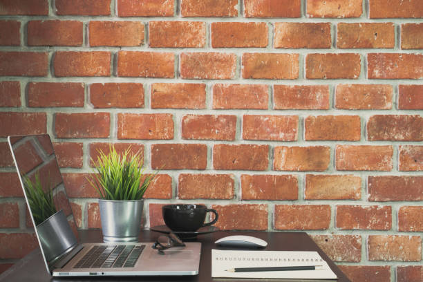 istock Desk of work table on brick wall background in office with laptop computer , notebook , calculator and a cup of coffee for creative marketing plan to success planning of company 970170160