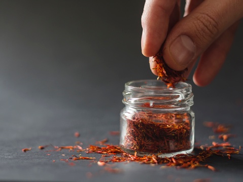 Hand picking saffron from a small jar