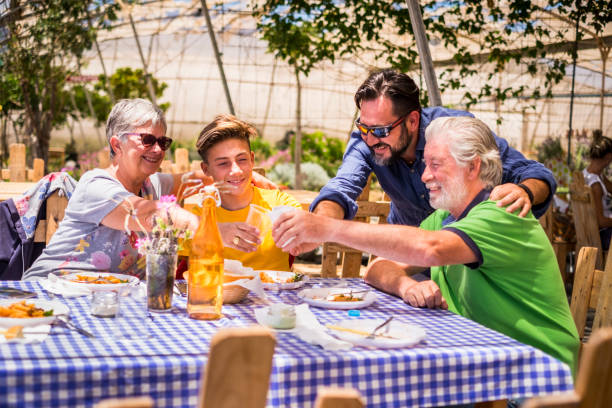 istock three different mixed generations at the table outdoor in a natural restaurant having fun together. drink and eat fresh food and have a nice leisure. people mixed ages grandfathers, father and son 970192638