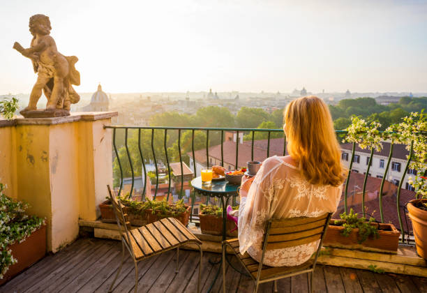 женщина сидит на балконе рано утром - rome italy skyline europe стоковые фото и изображения