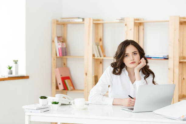istock Tired beautiful Businesswoman holding hand on head while working on computer and some business documents in bright office 970207430