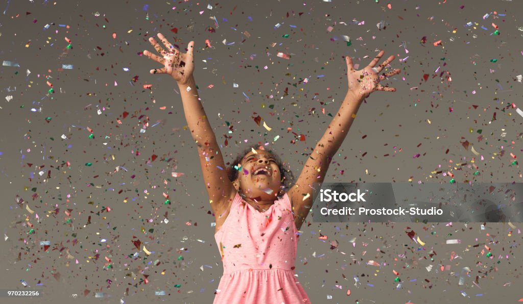 Happy black small girl at white studio background Happy african-american little girl at gray studio background, copy space. Portrait of beautiful child having fun with shiny confetti Child Stock Photo