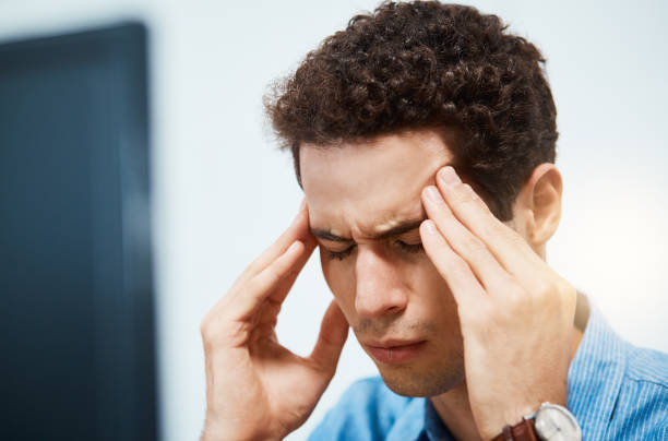 istock Young man with headache presses his temples 970232958