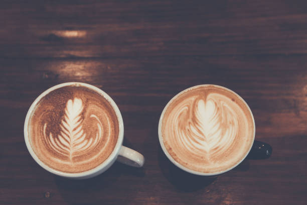 istock Two Coffee cup with latte art on wooden background . Selective focus white cup. 970241002