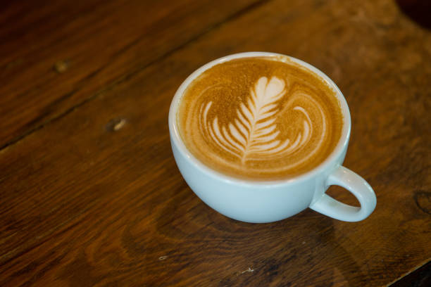 istock Coffee cup with latte art on wooden background . Selective focus 970241042