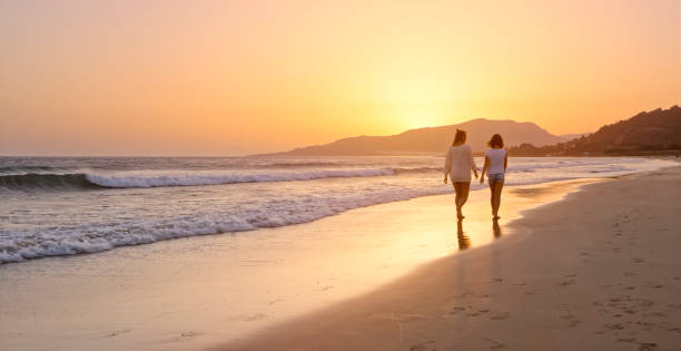 istock Mother and daughter walking on the beach 970248548