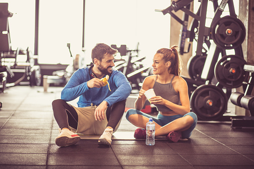 Young couple at gym eating healthy food after exercise.