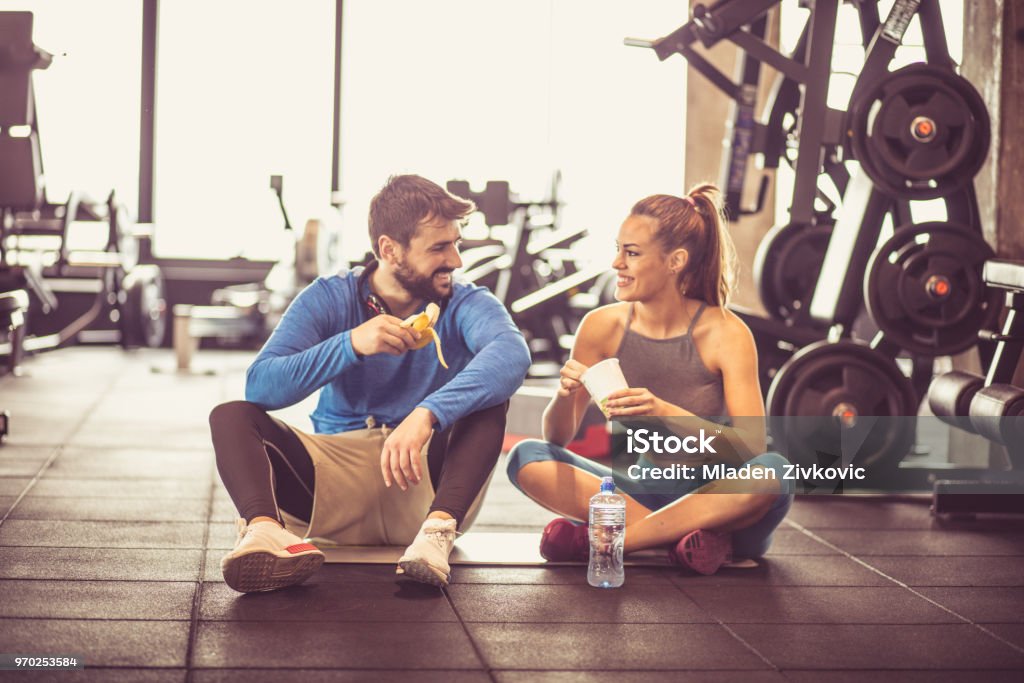 Healthy food. Young couple at gym eating healthy food after exercise. Gym Stock Photo