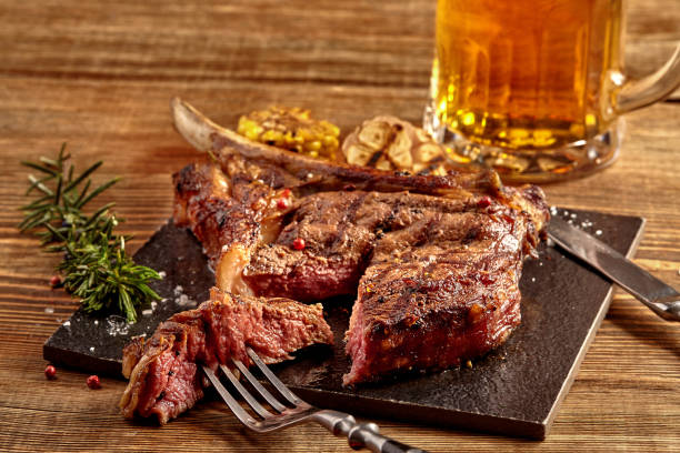 grillé, steak de boeuf de cowboy, verre de bière, des herbes et des épices sur un fond en bois. vue de dessus - steak argentina food silverware photos et images de collection
