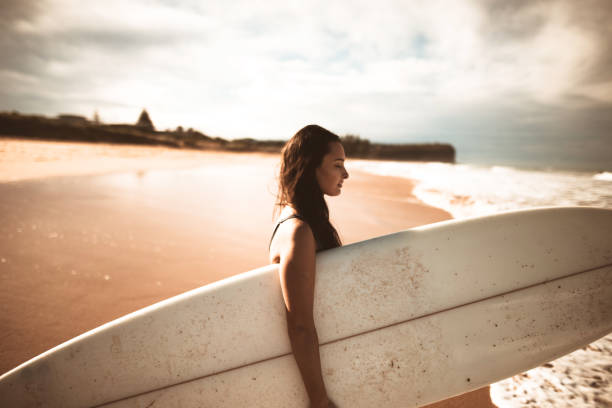 istock surfer woman standing on the beach with the surfboard 970267124
