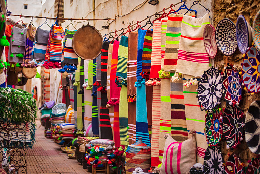colorful Moroccan textiles and souvenirs for sale in a street market - Essaouira souk, Morocco