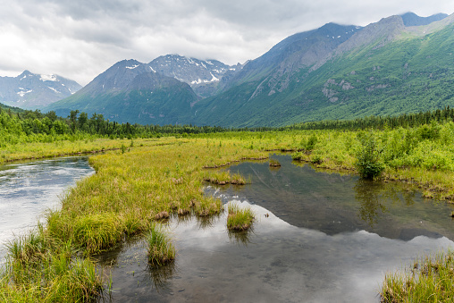 The Chugach Mountains are reflected in the waters of the Eagle River in Alaska.