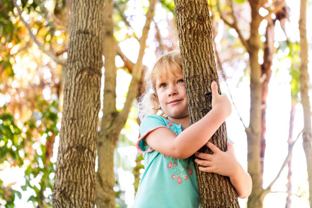 istock Girl embracing tree trunk at yard 970272166