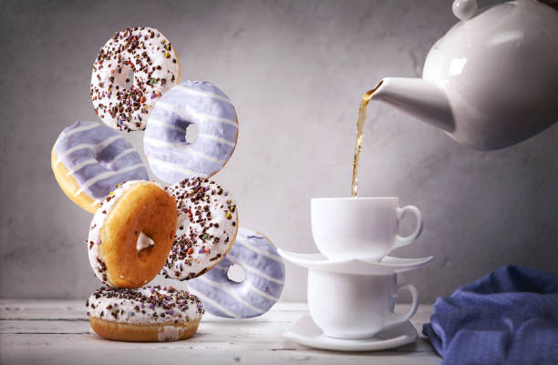 istock Still life with of the pouring into cap tea and falling down donuts 970284518