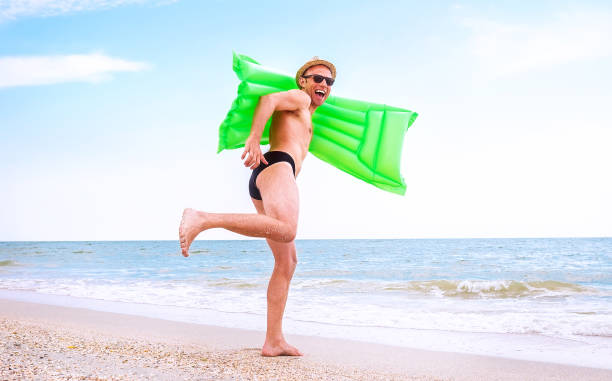 verrückter glücklicher mann mit schwimmen matratze läuft im meer - surfing surf wave extreme sports stock-fotos und bilder