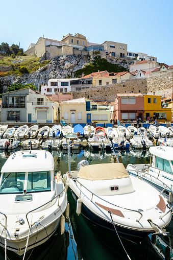 Marseille, France - May 19, 2018: The small port of the Vallon des Auffes by a sunny morning with modern and traditional boats moored in front of colorful cabanons and houses below the cliff.