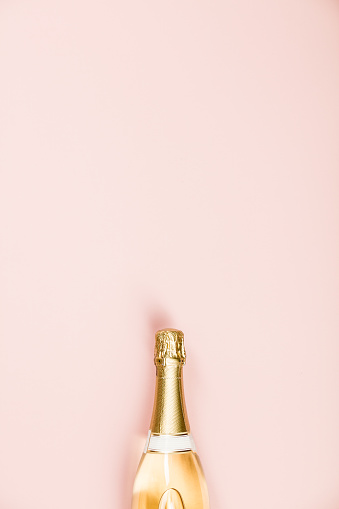 Flat lay of Celebration. Champagne bottle on pink background. Top view, copy space