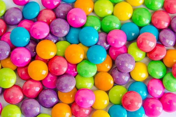 Pile of colorful sweet candy chocolates coated on white paper. colourful collection background