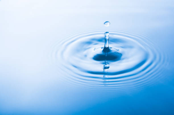 istock Water drop falling into water make waves. Water splash or water drop background. 970309092