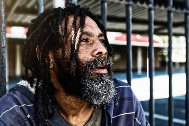 istock Homeless man deep in thought as he sits against a fence 970309830