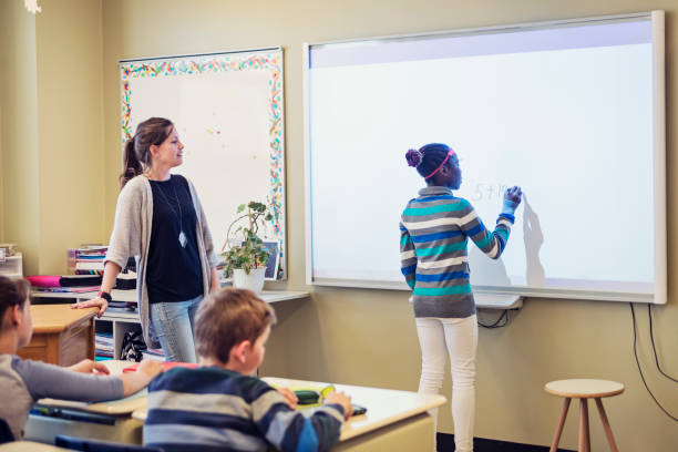 istock African-American girl writing on interactive whiteboard in classroom. 970317984